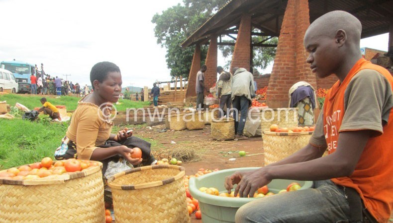 A woman and her son sort tomatoes at Jenda Market
