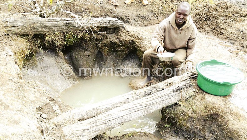 A villager fetches water from a dirty source