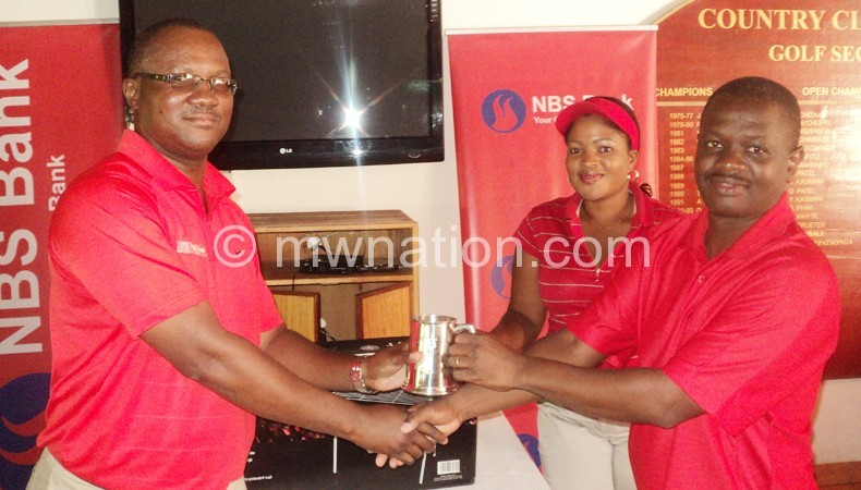 Tandwe (R) receives his prize from Siula as NBS marketing officer Lillian Kawaza looks on
