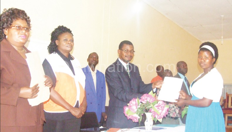Bamusi (L) Movete in suit presenting certificate to one of graduates