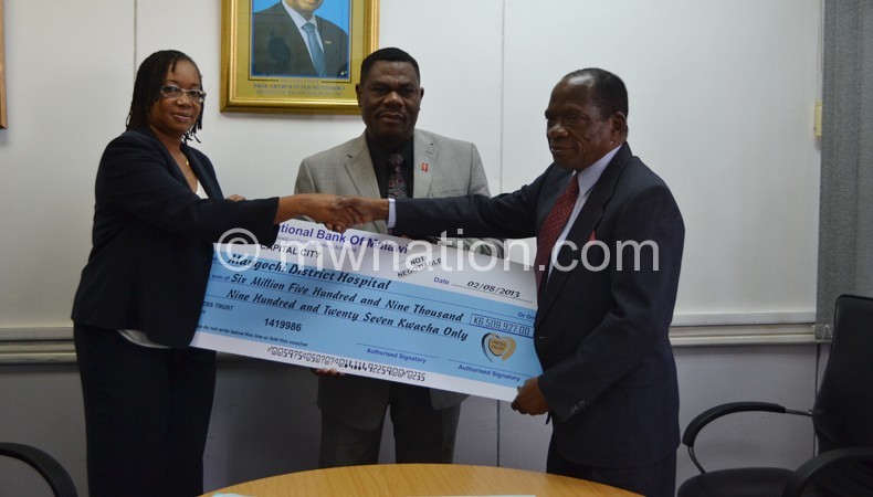 Banda receiving a dummy cheque from Kayambo as Press Trust Press Trust CEO Patrick Luhanga looks on