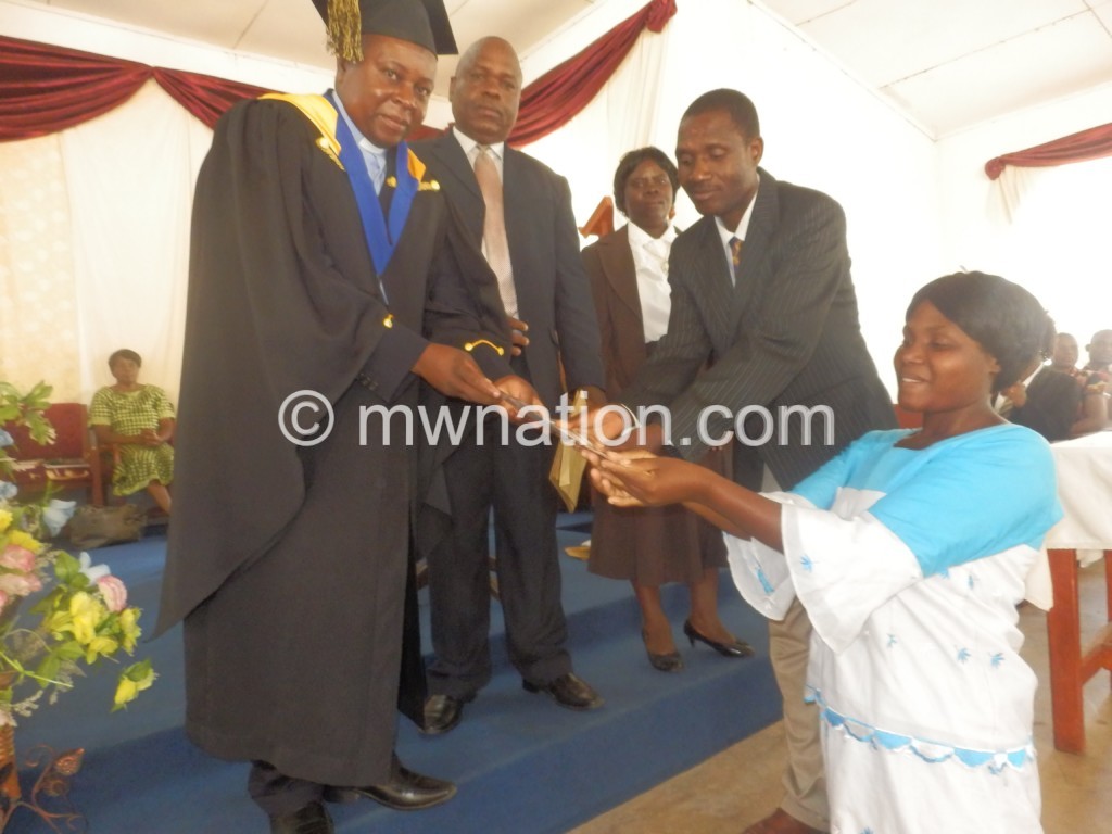  Kadango (in gown) presenting a certificate to one of the couples as Chifisi and wife (C) look on
