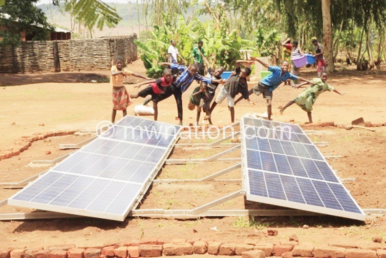 Children dance in front of solar panels