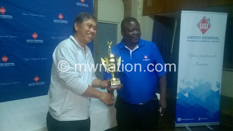 Guarino (L) receives his trophy from UGI operations manager Elias chipungu