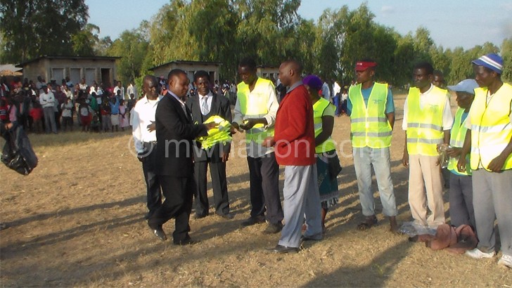 Njoloma (L) handing over reflector jackets to Kandulu (in maroon jacket)