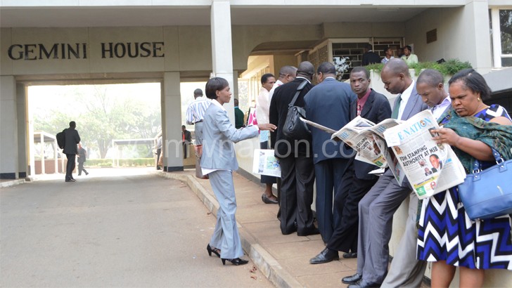 Some of the civil servants whiling away the time outside Gemini House before it was reopened later in the day