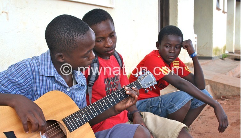 Some young musicians at the academy teach themselves how to play the guitar