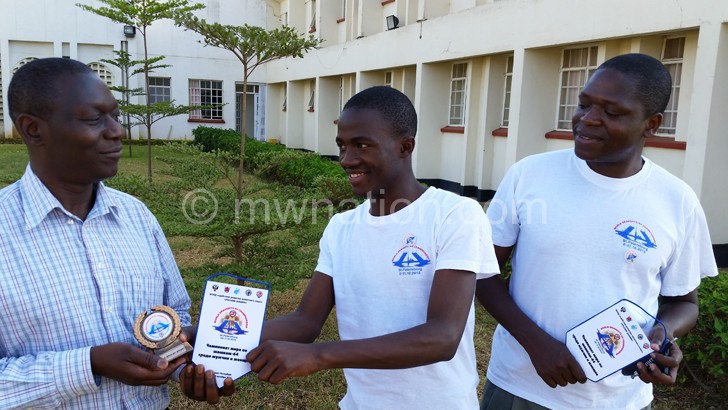Banda (C) present his trophy to Munthali (L)  as Nkhoma looks on 