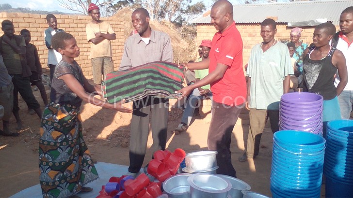 A beneficary receiving a blanket from Masingati(in red) 