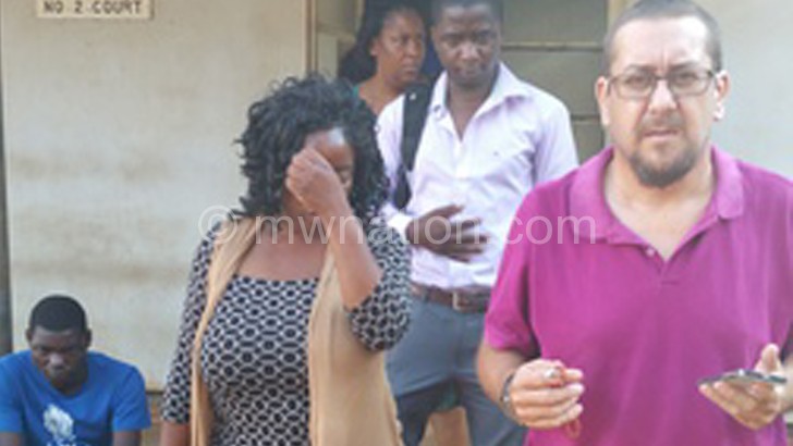 Ndovi (hiding her face) leaves court with her husband (R) and other well-wishers