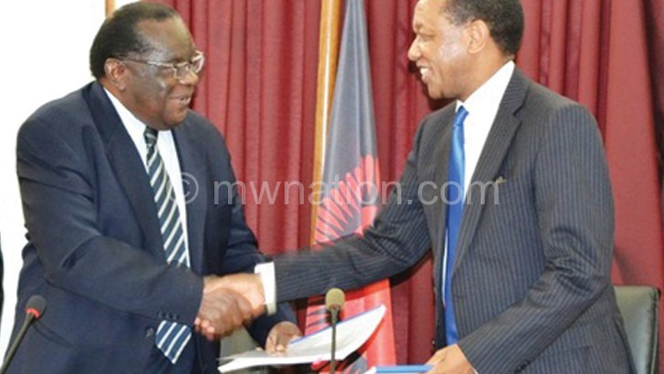 Gondwe and Mpinganjira exchange documents after the signing ceremony last year