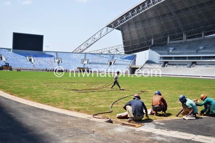 Workers carry out final touches on  the pitch