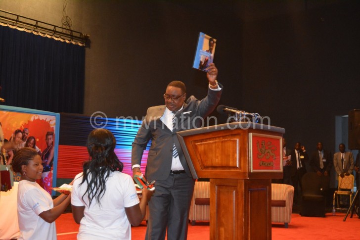 Mutharika shows off a booklet he received from  the youth at the conference 