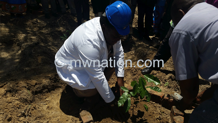 Mwanza (in white coat) planting a tree-seedling during the exercise
