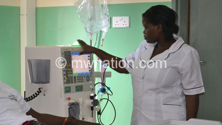 A nurse attending to a patient on a dialysis machine at QECH