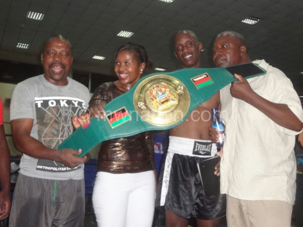 Mwando flanked by his wife Agnes (2ndL) and promoter Robin Alufandika (R) display his belt