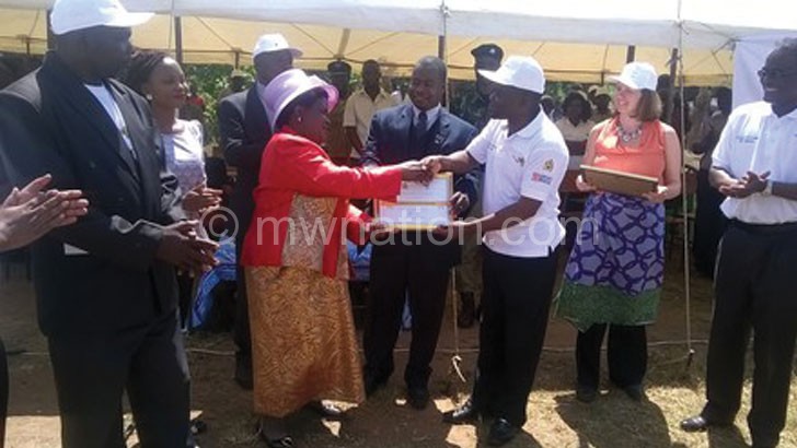 Kumpalume (R) handing a certificate to Kayembe  as other officials look on 