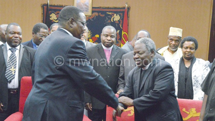 Mutharika shakes hands with PAC chairperson the Very Reverend Felix Chingota at the meeting