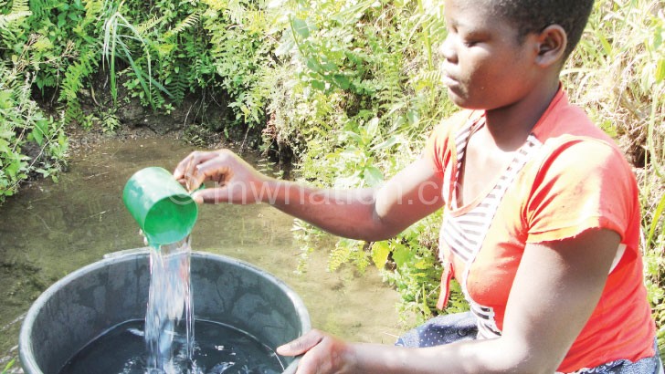 A woman collects water from an unsafe water source