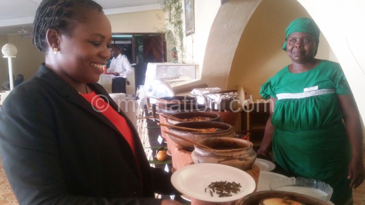 A diner scoops a spoonful of mphalabungu over a traditional lunch at Sunbird Lilongwe