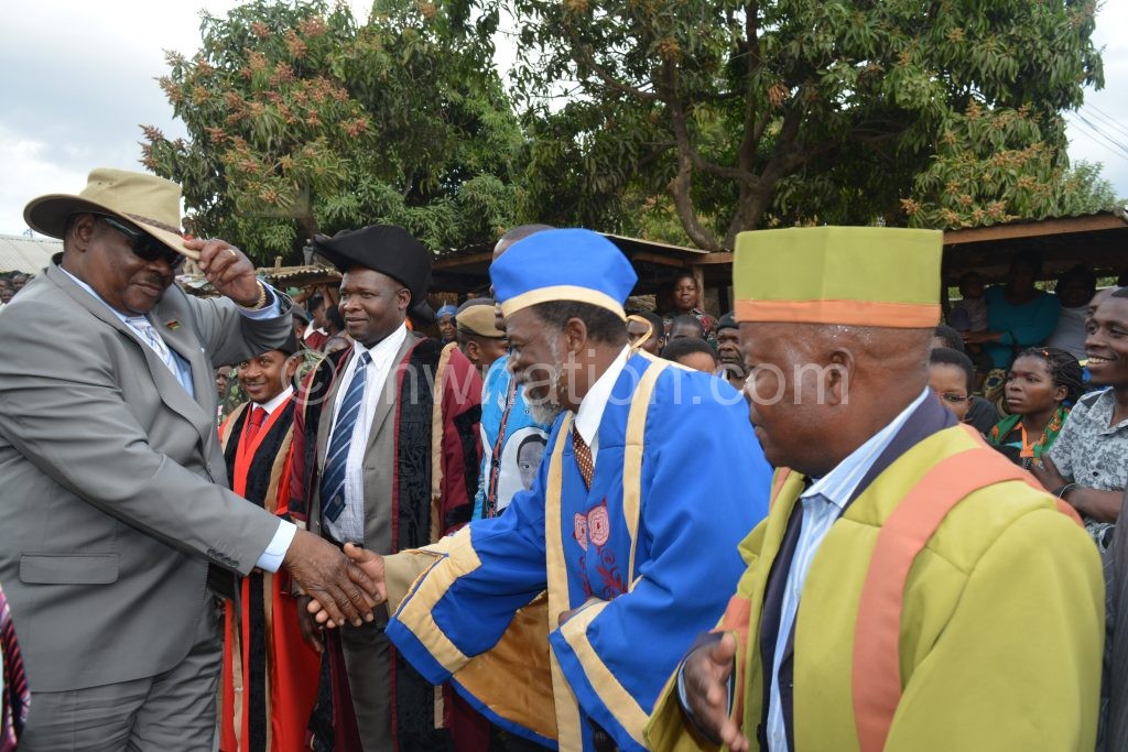 Mutharika shakes hands with T/A Kapeni as others look on