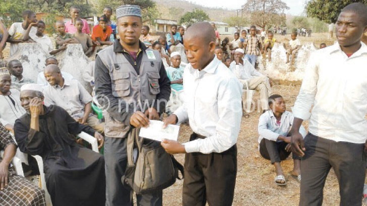 Benaa official Oscar Mudzumwe  gives money to a student