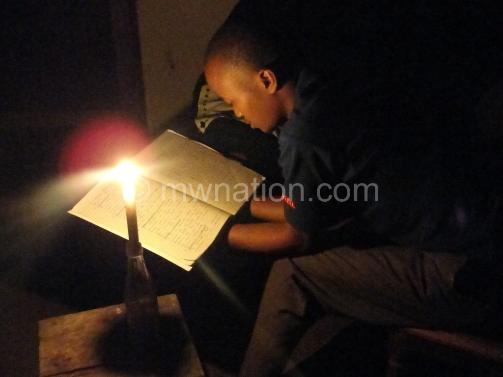A young man studying using a candle