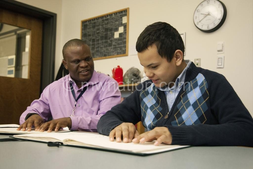 A teacher helps a  visually impaired child in class