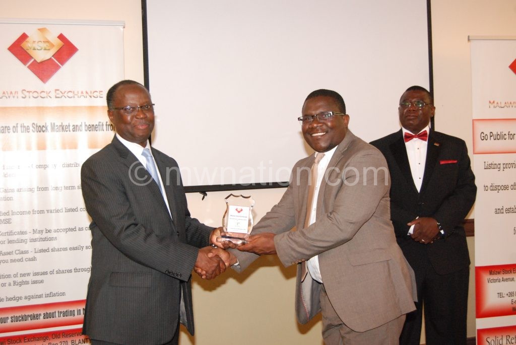 Chuka (L) presents an award to TNMs chief risk and audit officer Arnold Mbwana (C) as Kamanga looks on