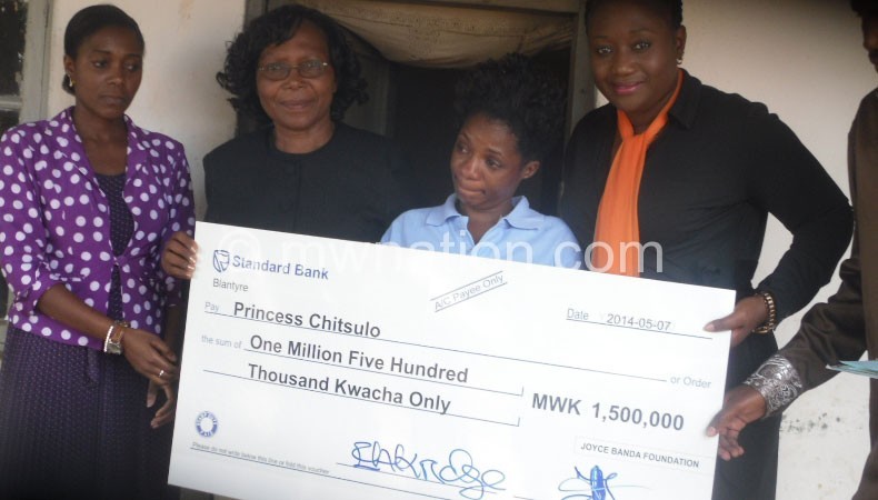 A tearful Chitsulo (C) receives a dummy cheque from Akridge (2nd-R) and Thandiwe Kampango as Phiri (R) and JBF official Unique Wachepa look on