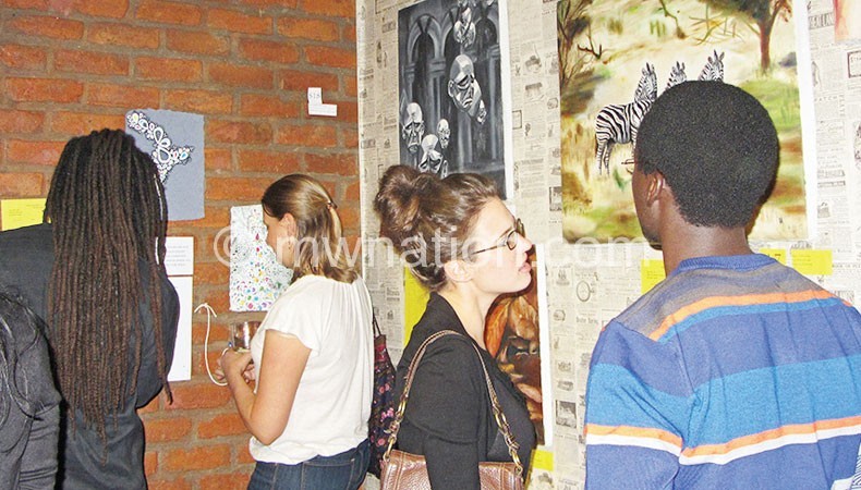 Patrons admire paintings during the exhibition