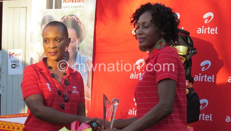 Mvula (R) receives her price from Airtel Malawi corporate executive Violet Phiri
