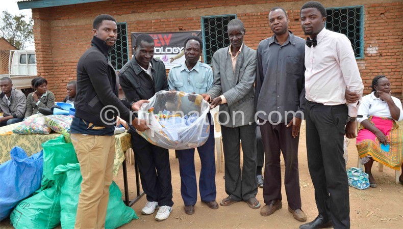 Jew Chapomba (R) and Young Kay presenting items to community elders in Chiradzulu