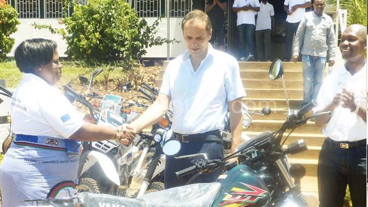 Gerrmann handing over the motorcycles and bicycles to Nice Trust board chairperson Susan Kaunda as other officials applaud