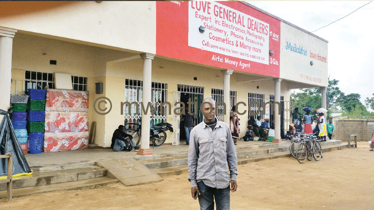 Gondwe standing in front of his shop