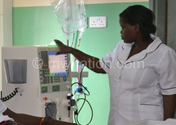 A nurse attending to a patient on a dialysis machine at QECH
