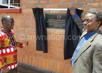 Nkhata Bay district commissioner Alex Mdooko (L) and Chirwa unveil the plaque at the school