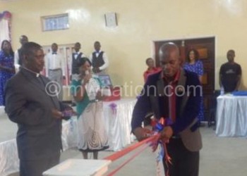 Kacheya (R) cuts the ribbon to launch the 
DVD as Rev Matikinya looks on