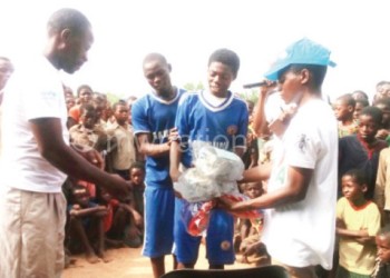 Malunga (in cap) presents 
footballs to a winning team