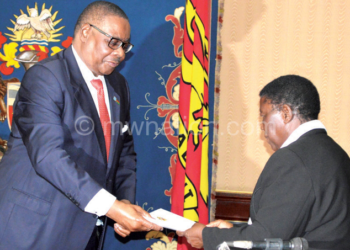 Mutharika (L) receives the report from Msosa