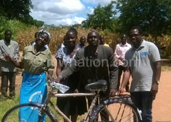 Some of the beneficiaries and officials pose with a bicycle