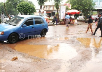 Motorists and pedestrians struggling to use a waterlogged road in Lilongwe City