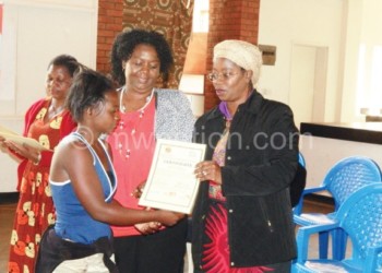 Makhumula (R) and Nyathi (C) present a certificate to one of the caregivers