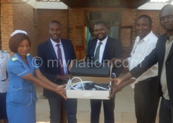 Alumando (3rdR) hands over the machine to Chibowa (3rdL) with the help of others