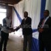 Syson (L) receives a certificate from Gwede while Tsogolani looks on