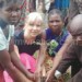 A missionary plants a tree with members of the community