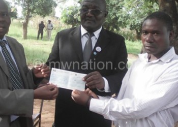 Mkumbwa (C) hands over a checque to community members