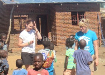 Touchstone officials interact with children in front of one of the houses