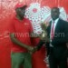 Minet managing director Delvin Khongono (L) presents a trophy to Songola