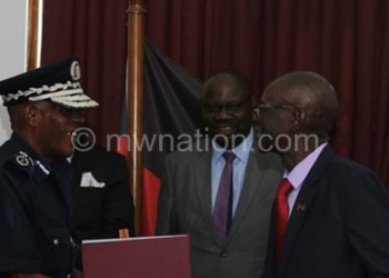 Nyondo (L) exchanges the MoU documents with 
Malata (R) as Botolo (C) looks on